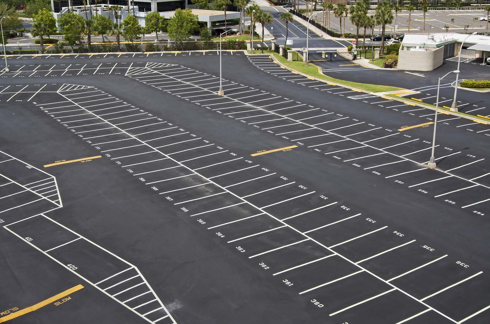 A large car park seen from above, its rows of white bay lines and numbered spaces laid out on dark asphalt